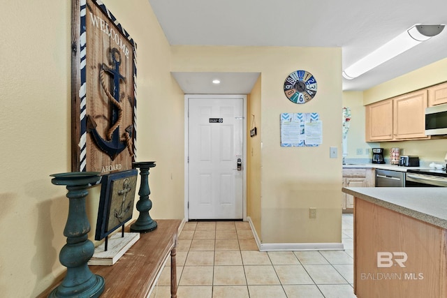 kitchen featuring stainless steel appliances, light tile patterned flooring, and light brown cabinets