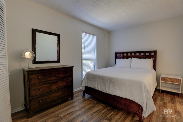 bedroom with a textured ceiling, baseboards, and wood finished floors