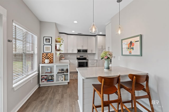 kitchen featuring open shelves, appliances with stainless steel finishes, wood finished floors, and white cabinetry