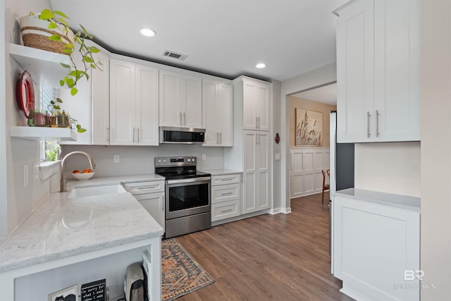 kitchen with a sink, stainless steel appliances, wood finished floors, white cabinetry, and open shelves