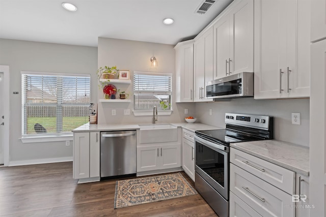 kitchen with a sink, recessed lighting, stainless steel appliances, white cabinets, and dark wood-style flooring