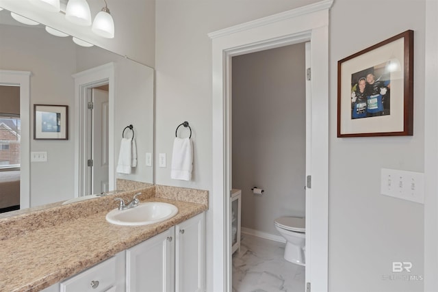 bathroom with marble finish floor, toilet, vanity, and baseboards