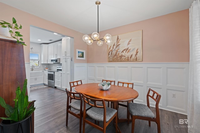 dining space with a decorative wall, a notable chandelier, dark wood-style floors, and a wainscoted wall