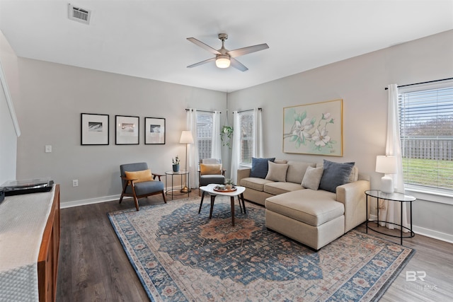 living room with dark wood finished floors, baseboards, visible vents, and ceiling fan