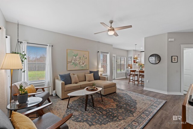 living room with ceiling fan, baseboards, and wood finished floors