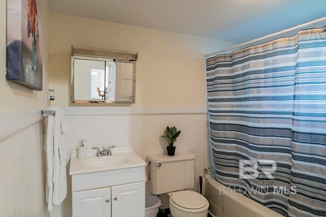 full bathroom featuring shower / tub combo, toilet, tile walls, and vanity