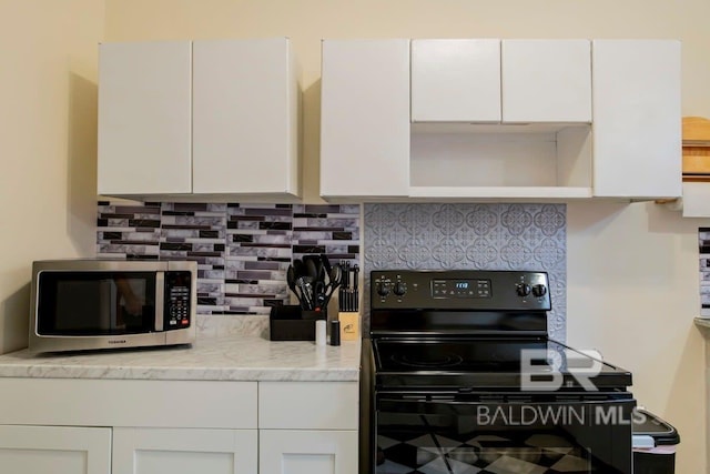 kitchen with black / electric stove, decorative backsplash, white cabinets, and light stone countertops