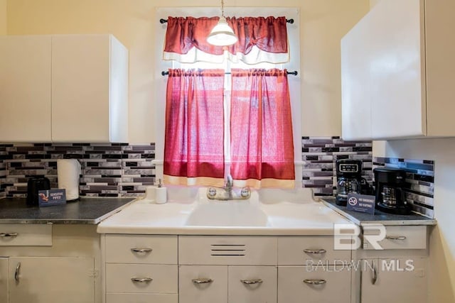 kitchen with sink, white cabinetry, hanging light fixtures, and decorative backsplash