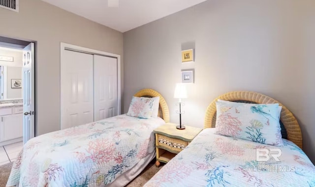 bedroom with light tile patterned floors, visible vents, a ceiling fan, ensuite bath, and a closet