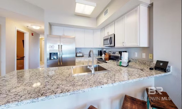 kitchen featuring stainless steel appliances, a peninsula, a sink, visible vents, and white cabinets