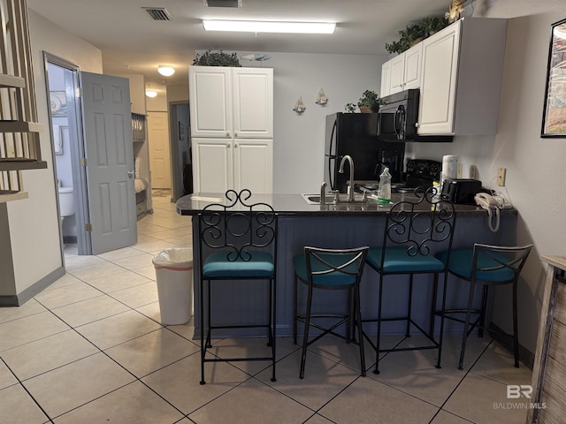 25805 Perdido Beach Blvd Unit 419, Orange Beach, AL 36561 - kitchen with a peninsula, white cabinetry, visible vents, black appliances, and dark countertops