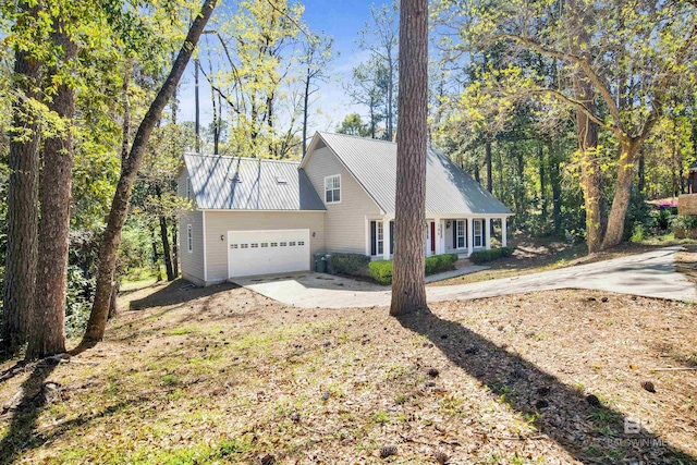 view of home's exterior featuring concrete driveway, metal roof, and an attached garage