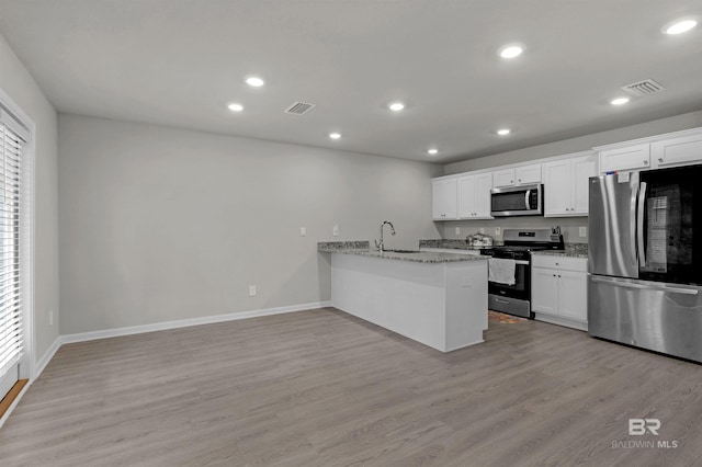 kitchen featuring white cabinets, light stone counters, kitchen peninsula, and stainless steel appliances