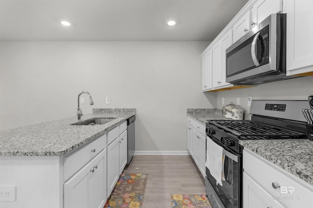 kitchen with light stone counters, stainless steel appliances, sink, light hardwood / wood-style flooring, and white cabinetry