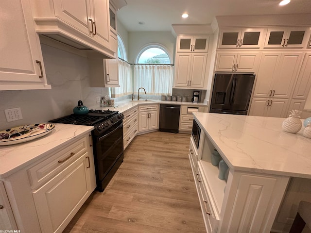 kitchen featuring sink, light hardwood / wood-style floors, black appliances, and white cabinetry