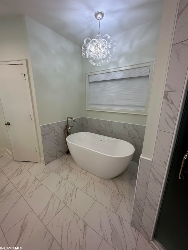 bathroom with tile walls, a tub, a chandelier, and tile flooring