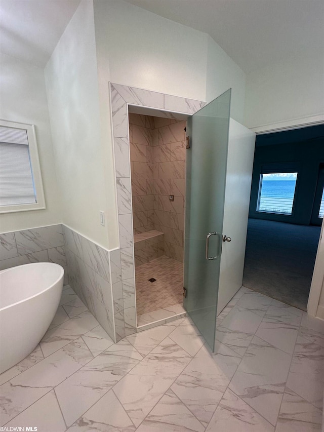 bathroom featuring independent shower and bath, tile walls, and tile floors