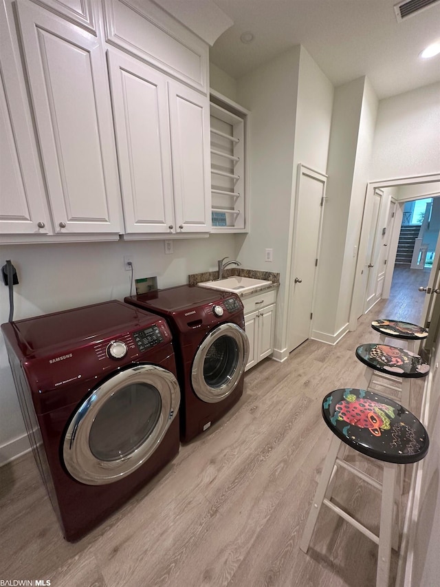 laundry area featuring cabinets, sink, light hardwood / wood-style flooring, hookup for a washing machine, and independent washer and dryer