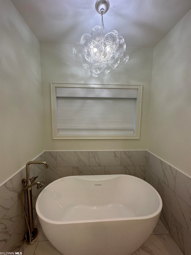 bathroom with tile walls, tile flooring, a chandelier, and a bathtub