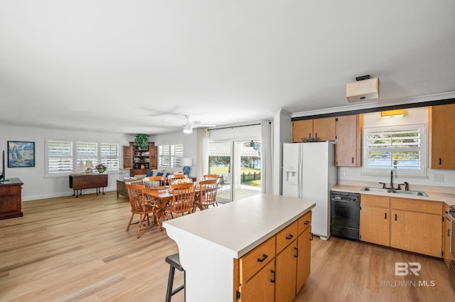 kitchen with white refrigerator with ice dispenser, light wood finished floors, light countertops, a sink, and dishwasher