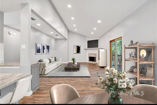 living room with a fireplace, high vaulted ceiling, and light hardwood / wood-style flooring