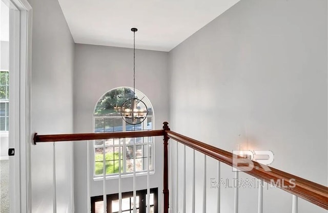 stairs featuring plenty of natural light and a notable chandelier