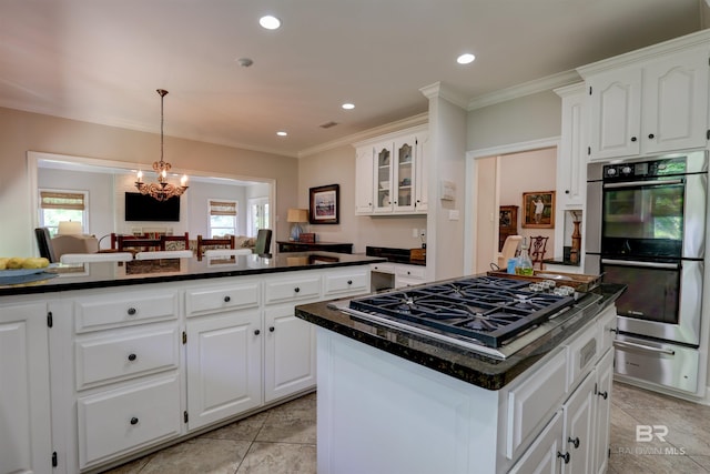 kitchen featuring light tile patterned floors, decorative light fixtures, appliances with stainless steel finishes, a kitchen island, and white cabinetry