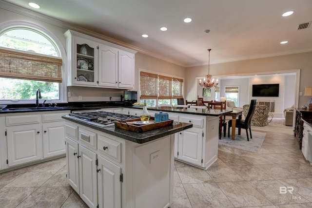 kitchen featuring stainless steel gas cooktop, sink, light tile patterned floors, a center island, and hanging light fixtures