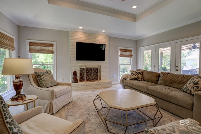 living room with a fireplace, a tray ceiling, and a healthy amount of sunlight