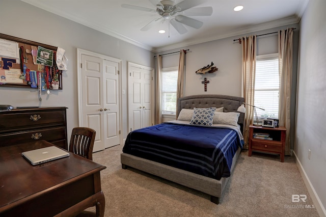 carpeted bedroom with ceiling fan, multiple closets, and ornamental molding