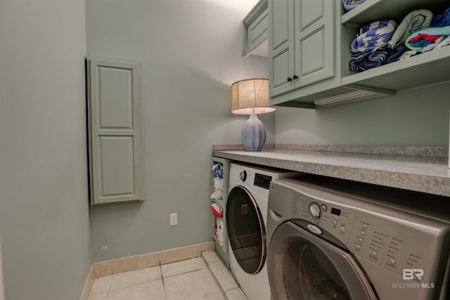 washroom featuring washing machine and clothes dryer, cabinets, and light tile patterned flooring