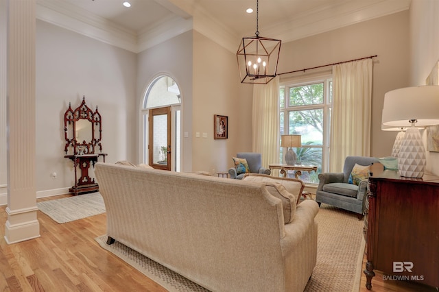 living room with light hardwood / wood-style floors, ornate columns, crown molding, and a chandelier