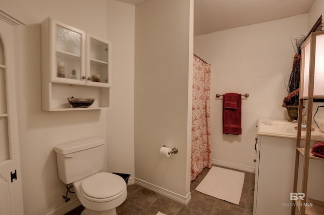 bathroom featuring tile patterned floors, toilet, a textured ceiling, and vanity