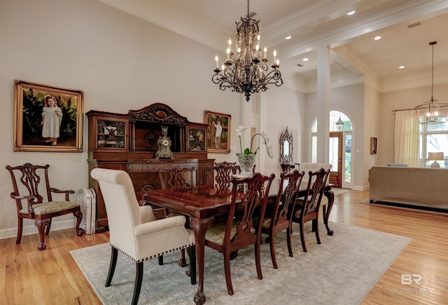 dining area with ornamental molding, beamed ceiling, light wood-type flooring, a notable chandelier, and a towering ceiling