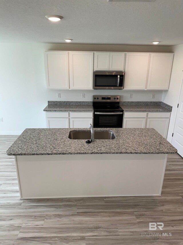 kitchen with white cabinets, black electric range, sink, and light stone counters