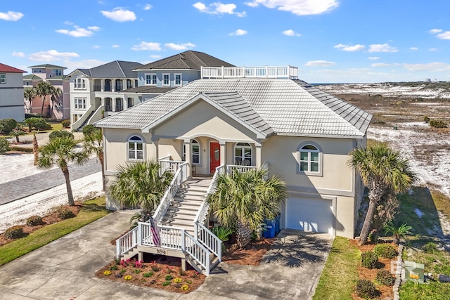 view of front of property featuring stairway, driveway, a porch, stucco siding, and a tile roof