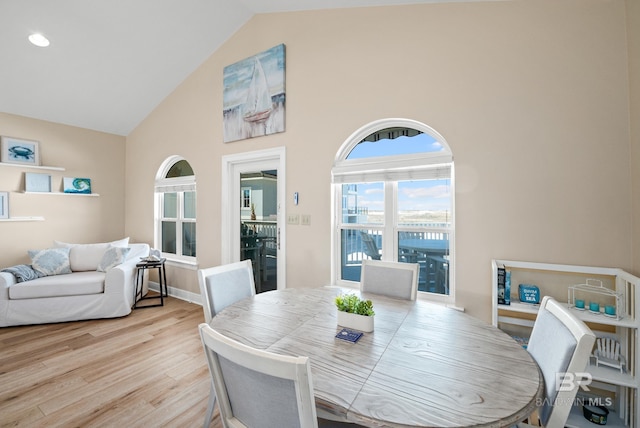 dining space with wood finished floors, baseboards, and high vaulted ceiling