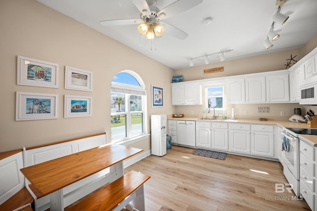 kitchen with a sink, white appliances, white cabinets, and light wood finished floors