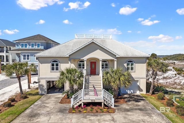 view of front of house featuring concrete driveway, stairway, a porch, and stucco siding