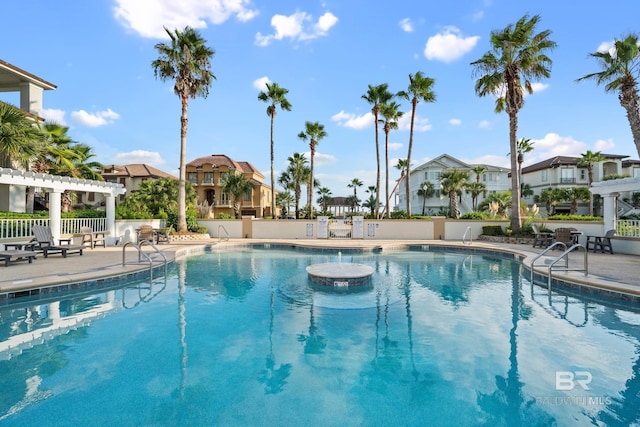 community pool featuring a patio, fence, a pergola, and a residential view