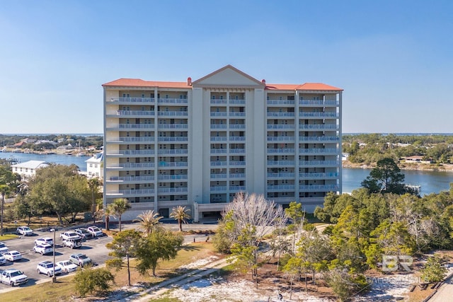 view of building exterior featuring uncovered parking and a water view