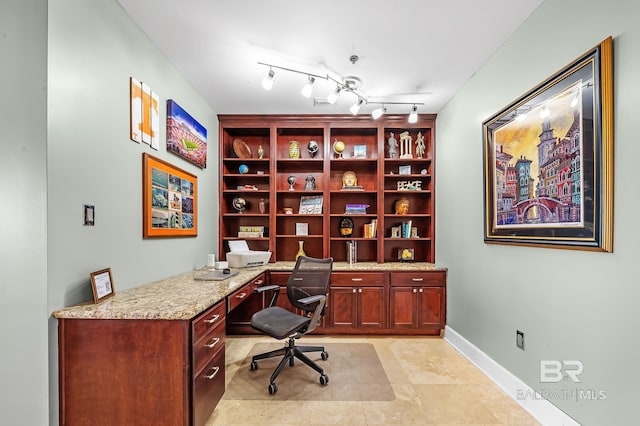 office space featuring baseboards, track lighting, and built in study area