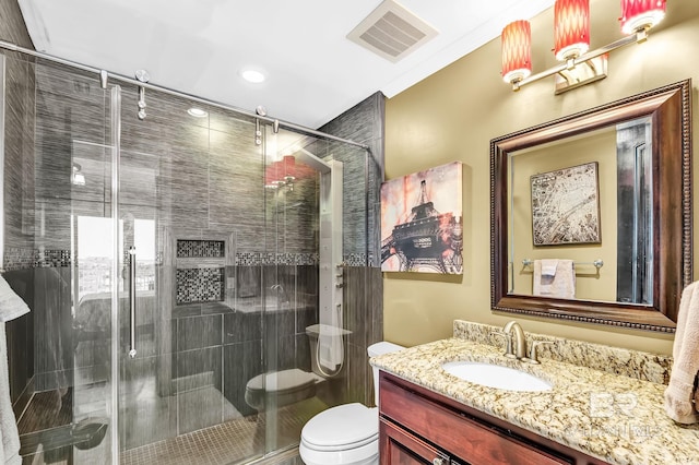 bathroom featuring toilet, a shower stall, visible vents, and vanity