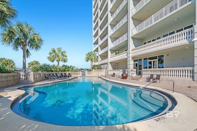 pool with a patio area and fence