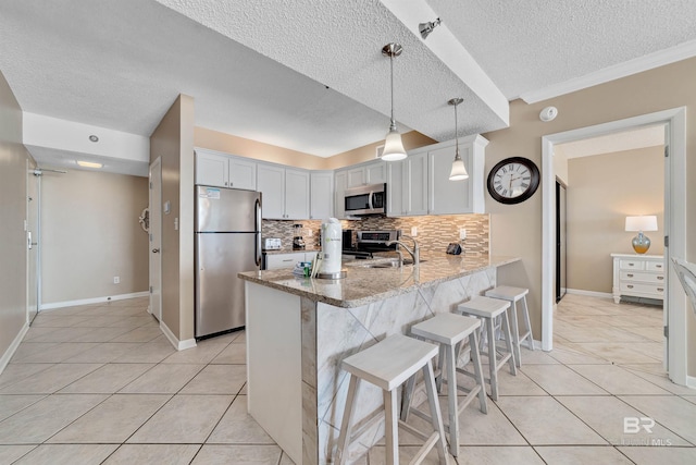 24720 Perdido Beach Blvd Unit 504, Orange Beach, AL 36561 - kitchen featuring stainless steel appliances, a peninsula, backsplash, a textured ceiling, and light tile patterned floors