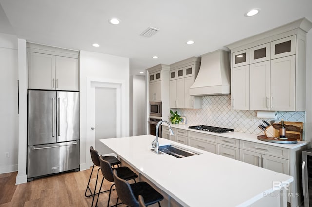 30531 Ono N Loop W, Orange Beach, AL 36561 - kitchen featuring stainless steel appliances, custom exhaust hood, a kitchen bar, decorative backsplash, and a center island with sink
