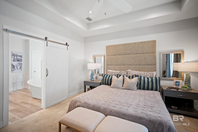 30531 Ono N Loop W, Orange Beach, AL 36561 - bedroom featuring a barn door, a raised ceiling, carpet, ensuite bath, and a ceiling fan