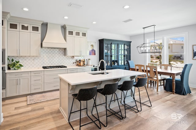 30531 Ono N Loop W, Orange Beach, AL 36561 - kitchen with custom exhaust hood, gas cooktop, a center island with sink, light countertops, and a kitchen breakfast bar