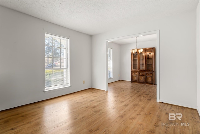 unfurnished room with a notable chandelier, a textured ceiling, and hardwood / wood-style flooring