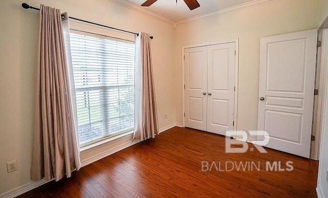 unfurnished bedroom featuring crown molding, dark hardwood / wood-style flooring, ceiling fan, and a closet